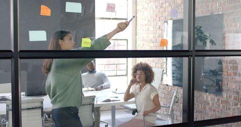 Diverse Team Brainstorming in Modern Office with Glass Board