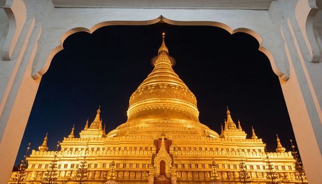 Framed golden pagoda at night under scalloped arch with illuminated stupa and spires
