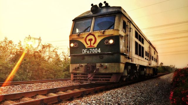 Diesel locomotive running along the railway track at sunset. Useful for transportation-themed visuals, industrial projects, travel and adventure content, and nostalgia-related designs.