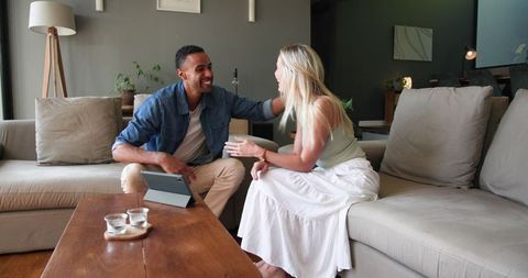 Joyful couple sharing engagement news via tablet at home