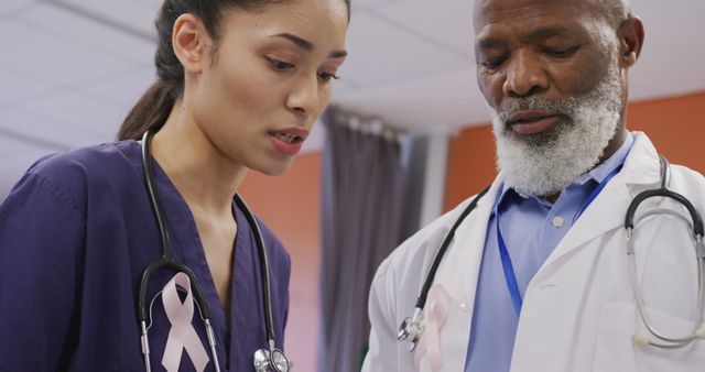 Two diverse male and female doctors wearing cancer awareness ribbons talking at hospital - Download Free Stock Photos Pikwizard.com