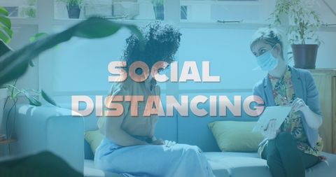 Colleagues talking on sofa practicing social distancing in office