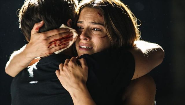 Embracing wounded partner while pressing bloodstained cloth, crying woman finding relief
