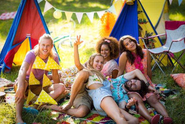 Group of friends enjoying a sunny day at a colorful campsite in a park. Ideal for use in advertisements, travel brochures, social media posts, and articles about outdoor activities, summer vacations, and friendship.