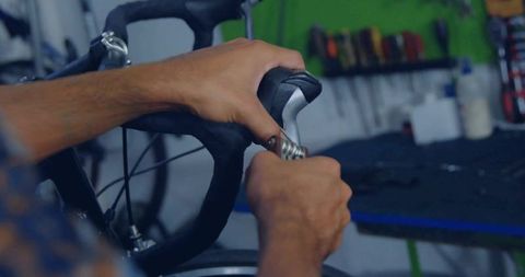 Bicycle maintenance in workshop with tools in background