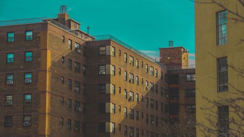 Golden Brick Apartment Blocks Under Teal Sky Casting Long Shadows