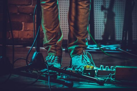 Musician standing with guitar pedals on stage