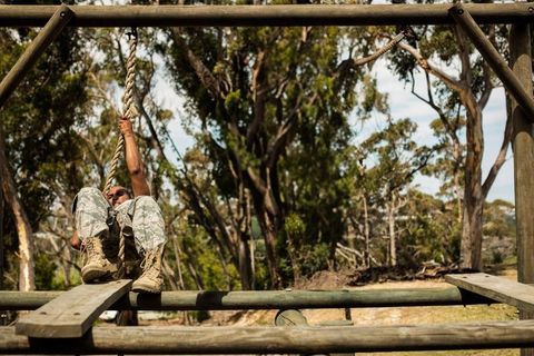 Woman in camouflage navigating rope obstacle on course
