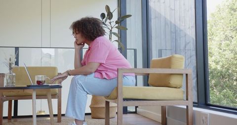 Focused Woman Working on Laptop at Home in Bright Living Room