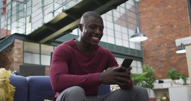 Smiling man using smartphone in modern urban apartment - Download Free Stock Images Pikwizard.com