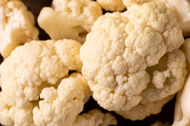Close-up of fresh white cauliflower florets. Ideal for use in articles or advertisements about organic food, healthy eating, vegetarian and vegan diets, and cooking ingredients. Perfect for food blogs, recipe websites, and nutritional guides.