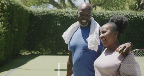 Senior African American Couple Walking with Tennis Rackets at Court