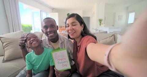 Happy father's day family selfie on sofa celebrating together in bright living room