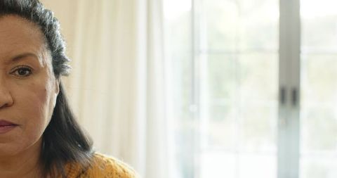 Woman looking through curtains, contemplative home setting