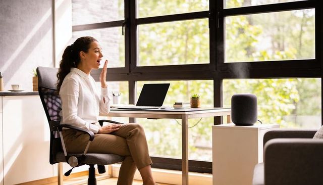 Working woman using smart speaker for voice meeting in bright minimal home office