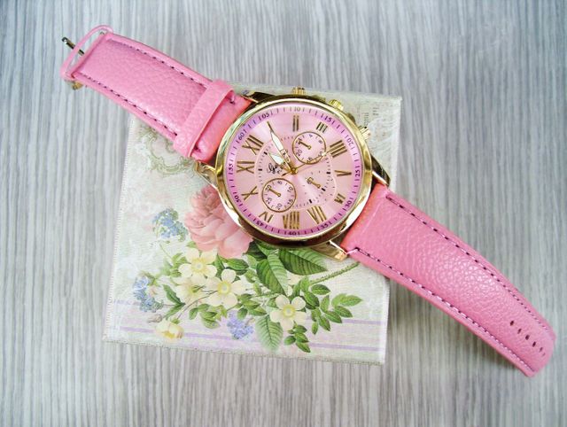Chic pink wristwatch featuring Roman numerals, displayed on a floral-designed box. Ideal for fashion or luxury accessory promotions, lifestyle blogs, and product advertisements focusing on stylish and elegant details.