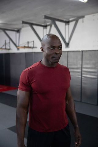 African american athlete standing confident in dojo wearing maroon shirt and black shorts