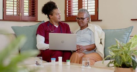 Healthcare Professional Assisting Senior Woman with Online Consultation at Home