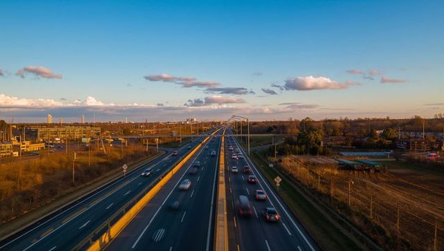 Flowing traffic on golden hour aerial highway stretching toward horizon suburban corridor