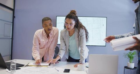 Architects Brainstorming Over Blueprints in Modern Conference Room