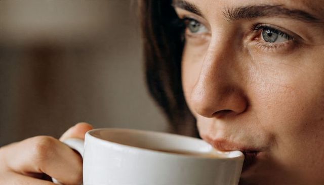 Intimate closeup portrait of woman sipping coffee, showing serene morning ritual