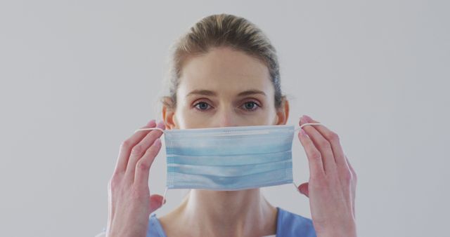 Healthcare Worker Adjusting Face Mask with Focused Expression - Download Free Stock Images Pikwizard.com