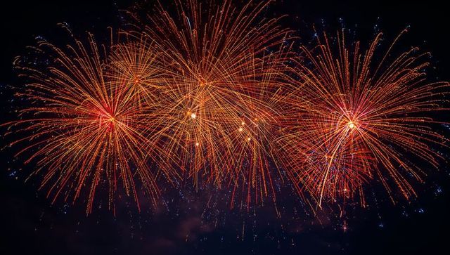 Bright orange and red fireworks lighting up night sky