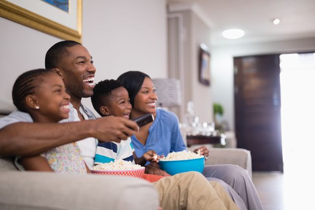 Cheerful family having popcorn while watching television - Download Free Stock Photos Pikwizard.com