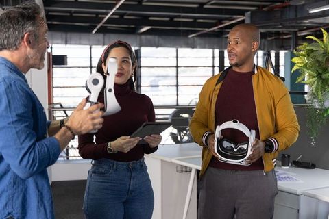 Multicultural team evaluating virtual reality headset components in modern open office