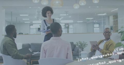 Young professional presenting to collaborative team in modern open-plan lounge with tablet