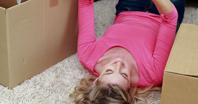 Woman Lying on Carpet Next to Moving Boxes, Relaxing with Eyes Closed - Download Free Stock Images Pikwizard.com