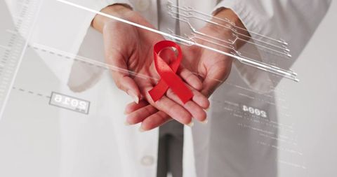 Healthcare professional holding red aids awareness ribbon with digital medical overlay