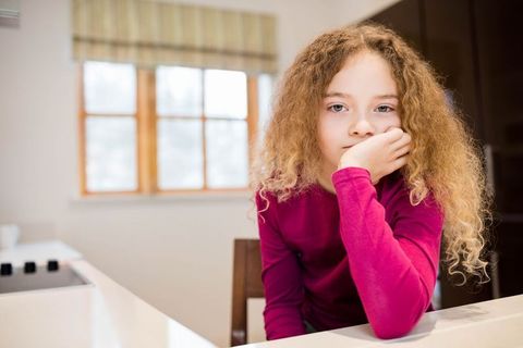 Pensive Young Girl Relaxing at Kitchen Counter in Sunlit Home