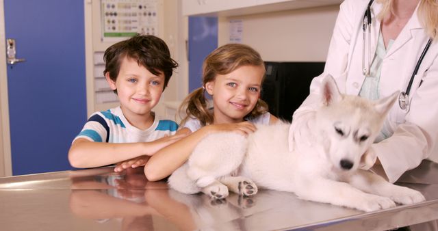 Two children smiling while standing next to a puppy and veterinarian, creating a warm and caring environment. Useful for depicting veterinary visits, animal care scenarios, childhood joy, family activities, and pet health awareness.