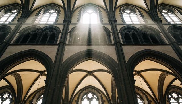 Sunlight pouring through gothic cathedral clerestory illuminating ribbed vaults