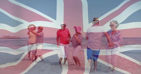 Union jack overlay on seniors strolling barefoot and holding hands on sunny beach
