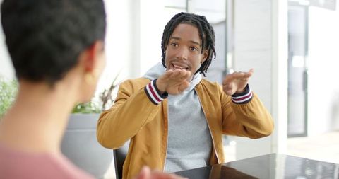 Young professional gesturing during collaborative office meeting with diverse coworker