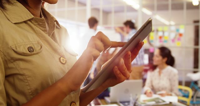 Woman Using Tablet in Creative Office with Team Collaborating in Background - Download Free Stock Images Pikwizard.com