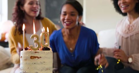 Women Enjoying 30th Birthday Party with Candles and Cake Celebration
