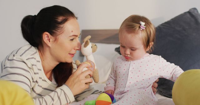 Caucasian mother and baby playing with toys on the bed at home. motherhood, love and childcare concept