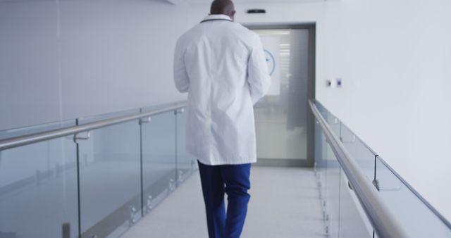 Back view of african american male doctor walking through hospital corridor. medicine, health and healthcare services.