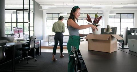 Colleagues unpacking office boxes in modern workspace