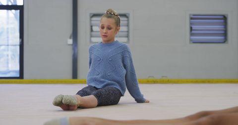 Caucasian girl stretching in sports hall for gymnastics
