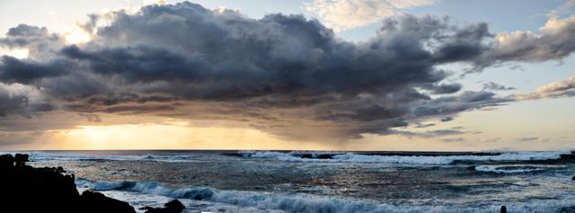 Panoramic scene of a dramatic ocean sunset with stormy clouds. Captures the contrast between tranquil sunset colors and the impending storm. Perfect for use in travel blogs, nature photography collections, or as eye-catching backgrounds for websites and presentations.