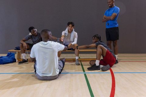 Diverse male athletes fist-bumping in gymnasium showing team unity and camaraderie