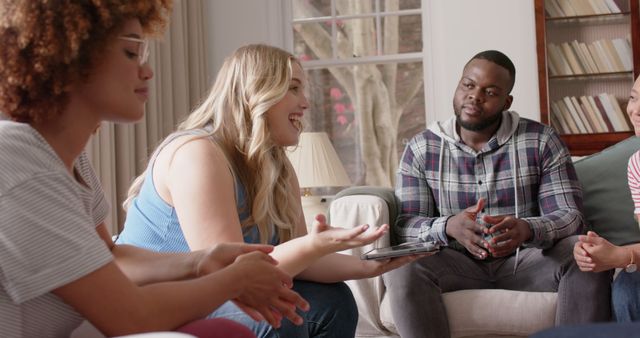 Diverse group of friends engaging in conversation in a cozy living room. Perfect for themes involving friendship, inclusivity, relaxation, social gatherings, and indoor activities.