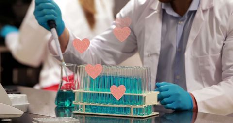 Male scientist using a pipette in a modern lab with heart graphics representing life sciences innovation. Suitable for illustrating scientific career images, modern research techniques, and hybrid tech-design visuals in presentations or educational material.