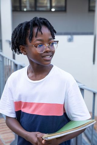 Teen boy with notebooks on urban campus walkway