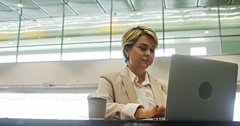 Businesswoman Working on Laptop at Airport Terminal