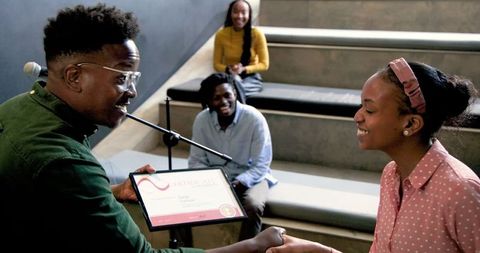 Smiling recipient receiving award in classroom setting